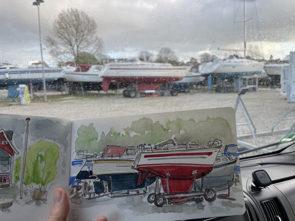 Foto - Blick aus der Windschutzscheibe auf die Boote - im Vordergrund das Skizzenbuch mit dem Aquarell dazu.