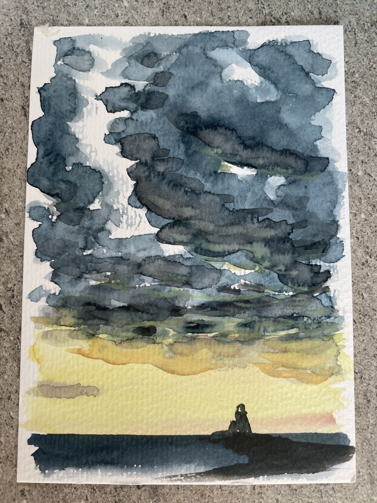 Dunkler Wolkenhimmel vor gelbscheinendem Sonnenuntergang - im unteren Bereich als Silhouette ein Horizont mit Aussichtsturm. Aquarell im Hochformat Postkarte.